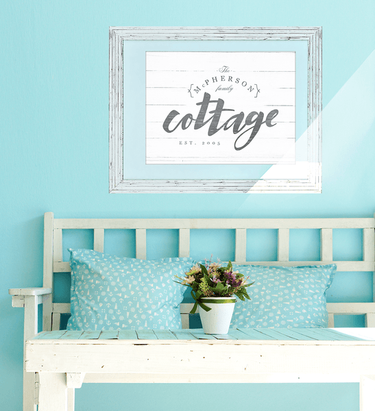 white and blue cottage room with a personalized print "Cottage" hanging on the wall above a vintage bench.