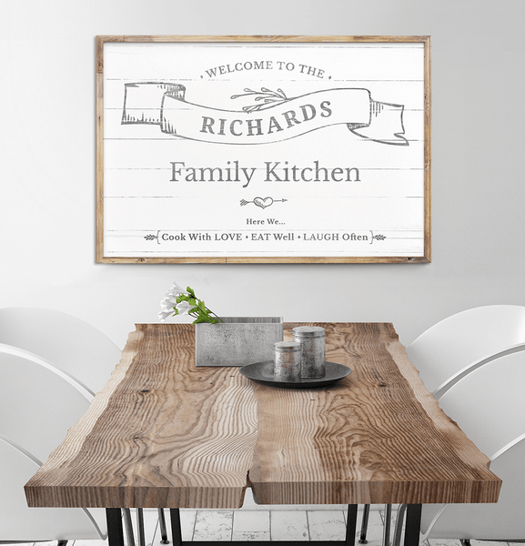 Framed Welcome To Our Kitchen personalized print hanging above a vintage dining table