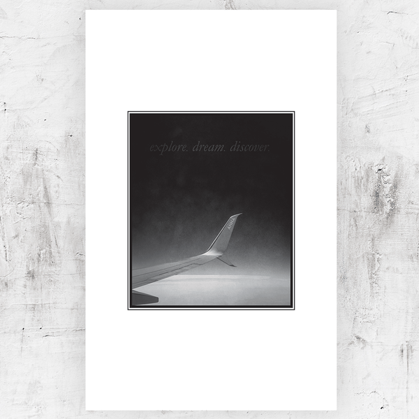 Black and white print of an airplane wing personalized with first name. Text on the print reads "Explore Dream Discover"