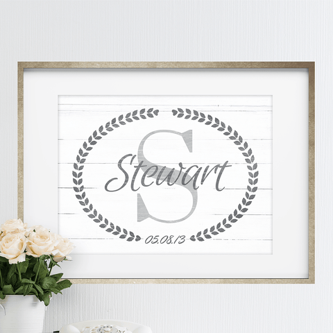 Framed Family Name print with a large initial and family name printed over it.